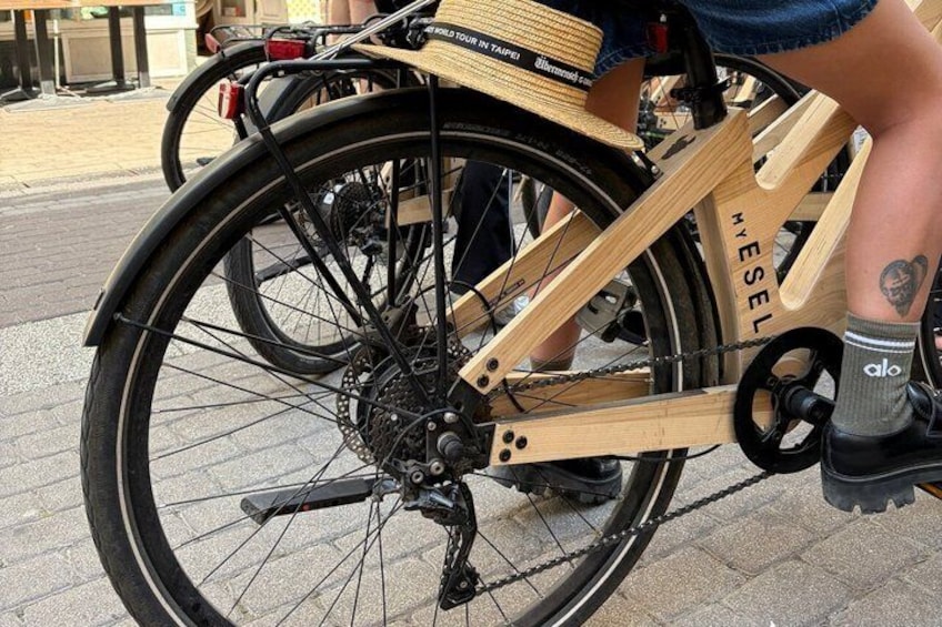 A wooden bicycle with a chain and gears, a rear wheel, and a seat. 2