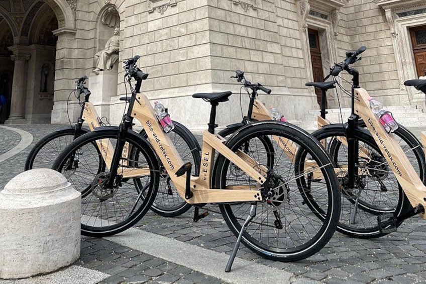 A row of bicycles parked in front of a historic building with stone architecture. 3