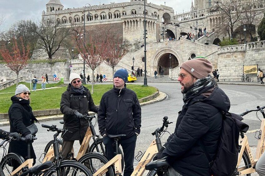 A group of people with bicycles in front of a historic stone building. 2
