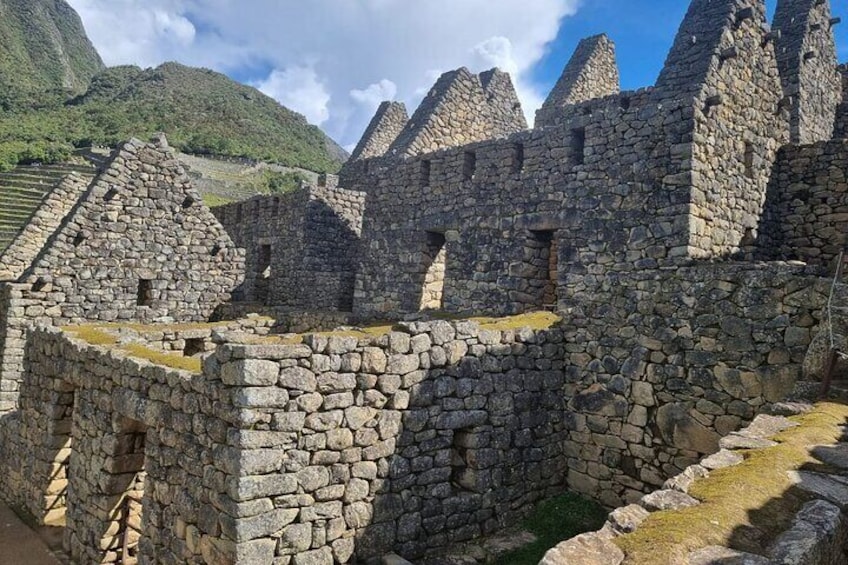Ancient stone ruins with stepped structures and a mountainous backdrop. 3