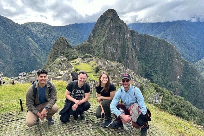 A group of people posing in front of Machu Picchu with the iconic mountain ruins in the background. 2