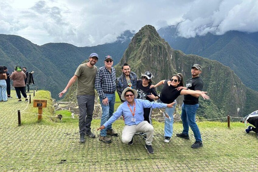 En gruppe mennesker poserer foran Machu Picchu med et bjerg i baggrunden. 5
