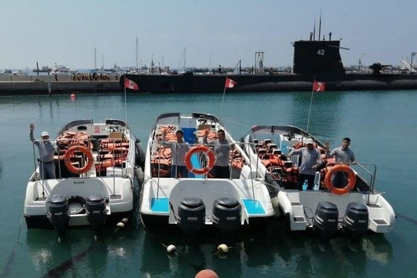 Three small boats docked at a pier with lifebuoys on board, a large ship in the background, and a clear sky. 4
