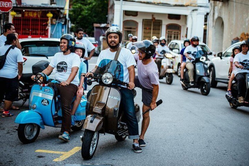 A street scene with people riding scooters and motorcycles, buildings in the background, and a sign with Chinese characters. 3