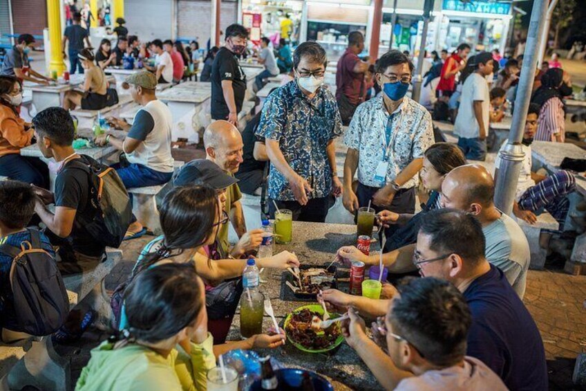 A crowded outdoor dining area with people eating and socializing. 5