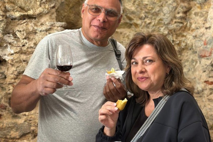 Due persone che tengono in mano cibo e un bicchiere di vino rosso. 3