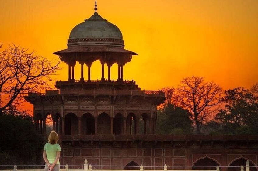 A historical building with a dome and arches, set against a sunset sky. 4