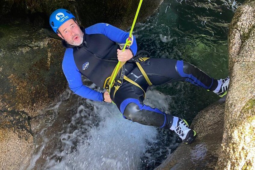 Une personne qui descend en rappel une falaise rocheuse, avec une rivière en contrebas. 3