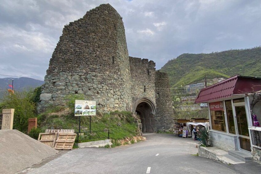 A stone tower with a pointed roof, a road leading to it, and a small building with a red roof to the right. 3