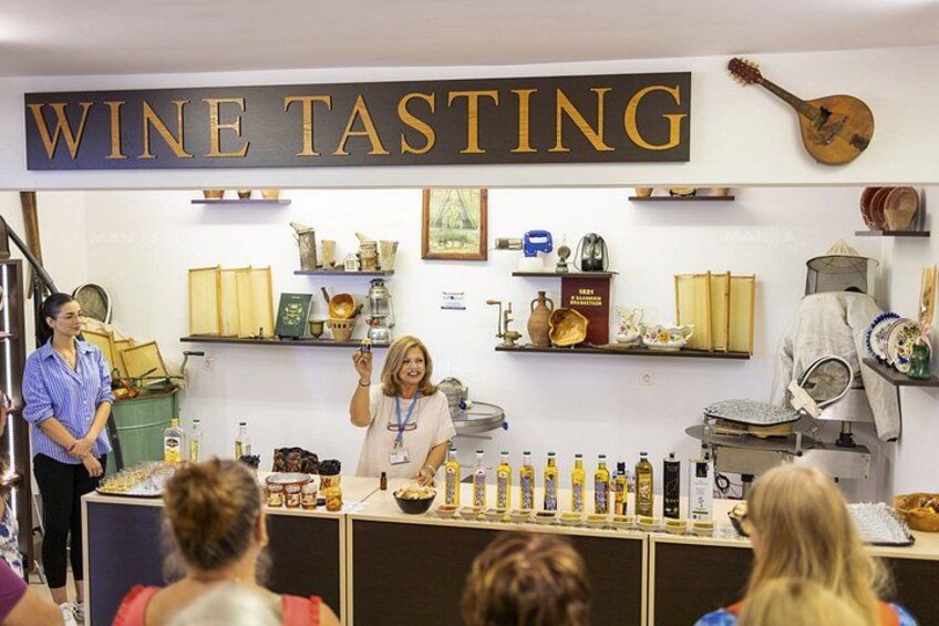 A wine tasting event with a sign reading 'WINE TASTING' above a counter displaying various bottles. 4