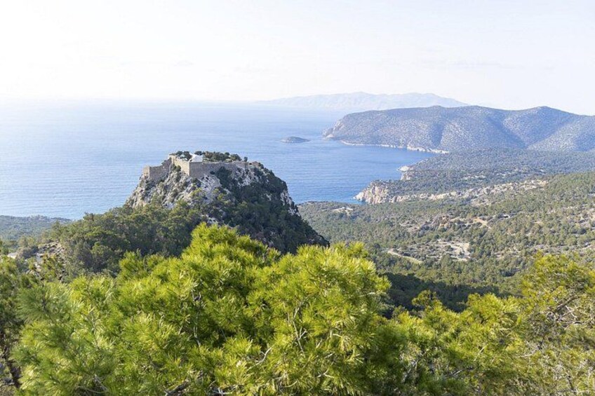 A mountainous landscape with a prominent rocky outcrop and a body of water in the distance. 3