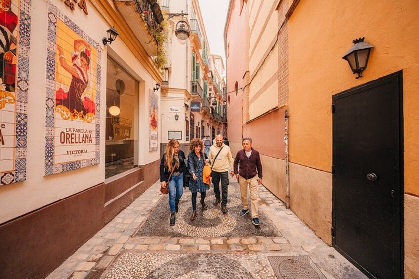 A narrow street with shops, a tiled pavement, and a black door. 2