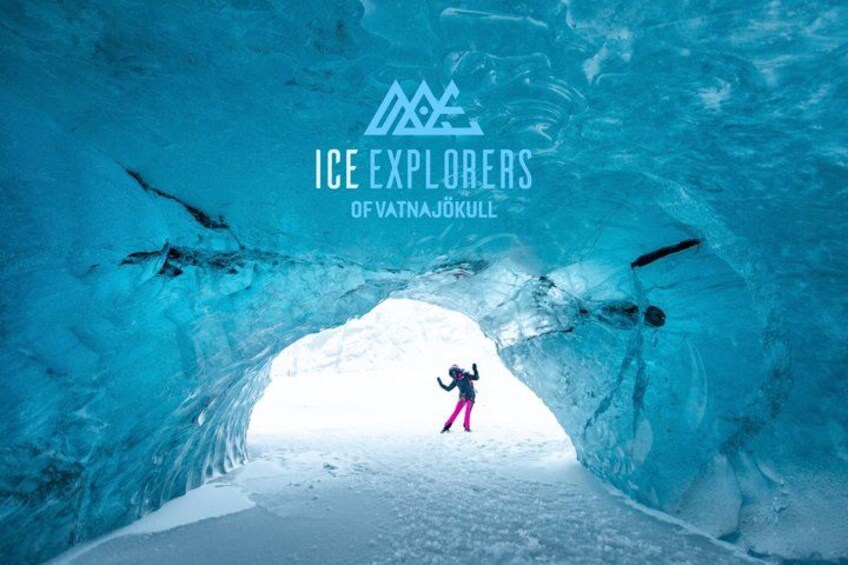 An ice cave with a person in pink attire exploring it. 1