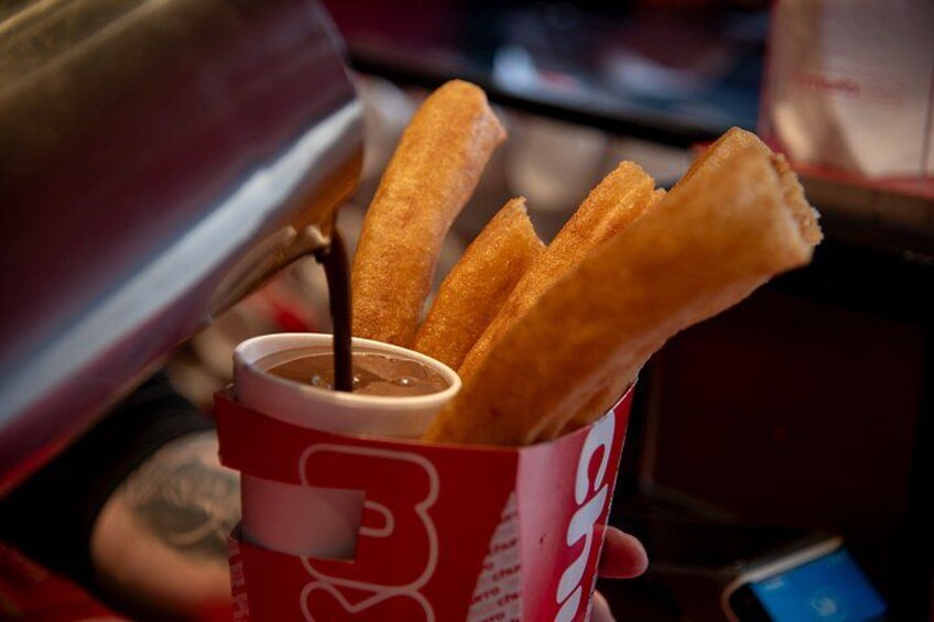 A cup of churros dipped in chocolate sauce. 2