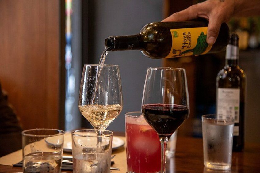 A hand pouring wine from a bottle into a glass. 3