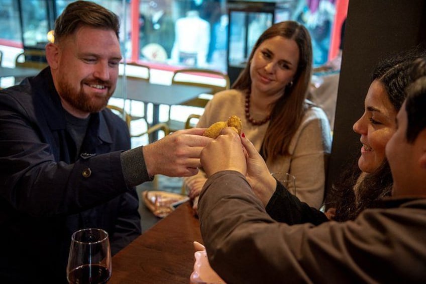 A person serving food to two others at a table in a restaurant. 4