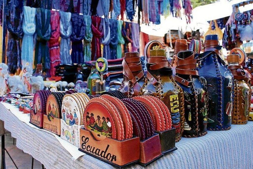 Une table où sont exposés divers articles en cuir, notamment des sacs et des bouteilles, dans un marché. 1