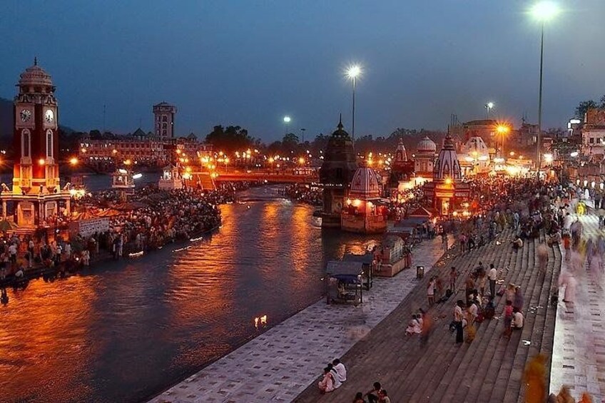 A river with a bridge, a clock tower, and illuminated buildings along the banks. 1