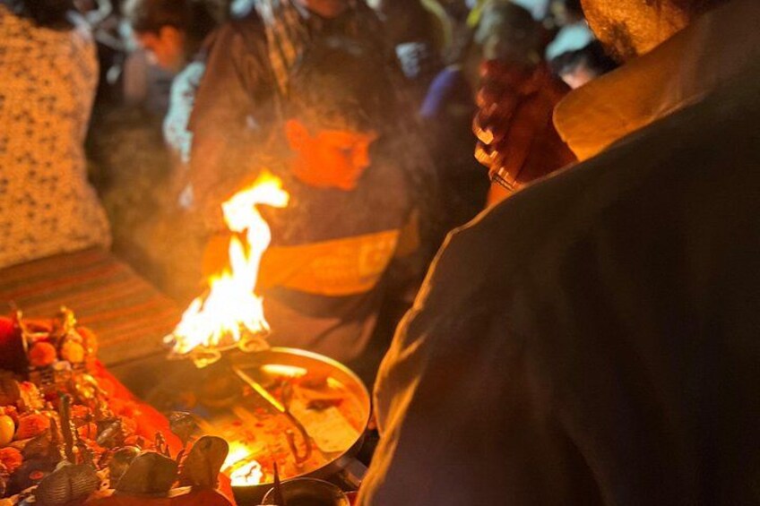A ceremonial fire with offerings, a crowd, and a person in traditional attire. 4