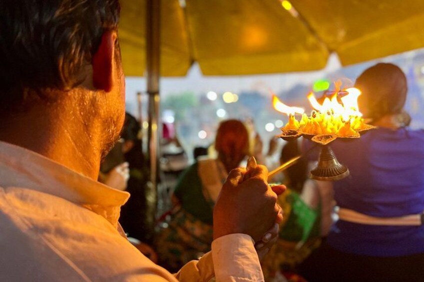 A person holding a lit oil lamp, likely used for a religious or cultural ceremony. 5