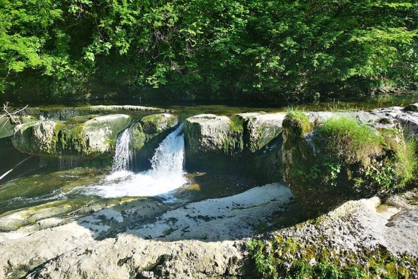 A waterfall cascading over rocks in a forested area. 2