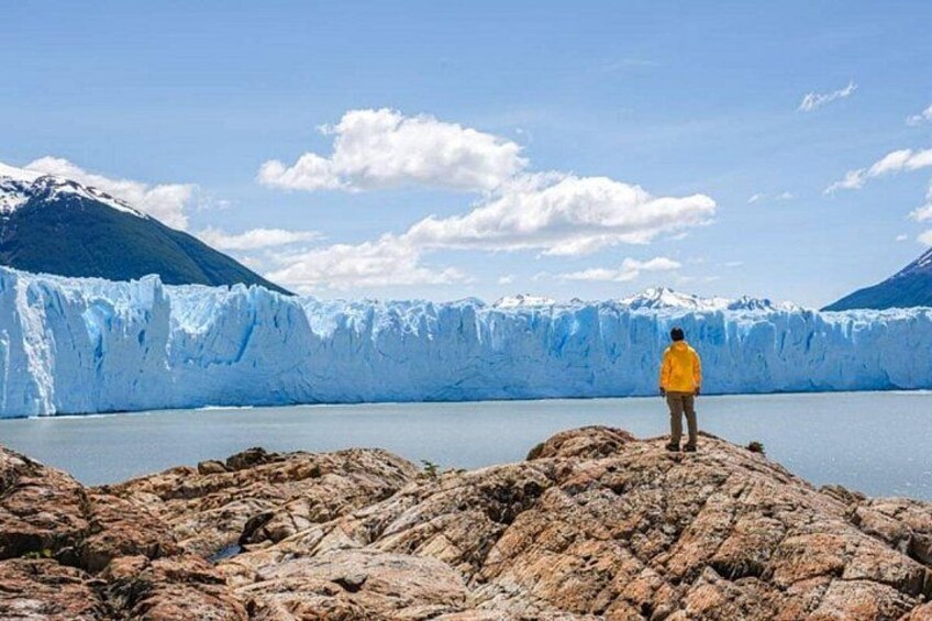 Un ghiacciaio con una persona che indossa un giubbotto giallo in piedi su una roccia. 4