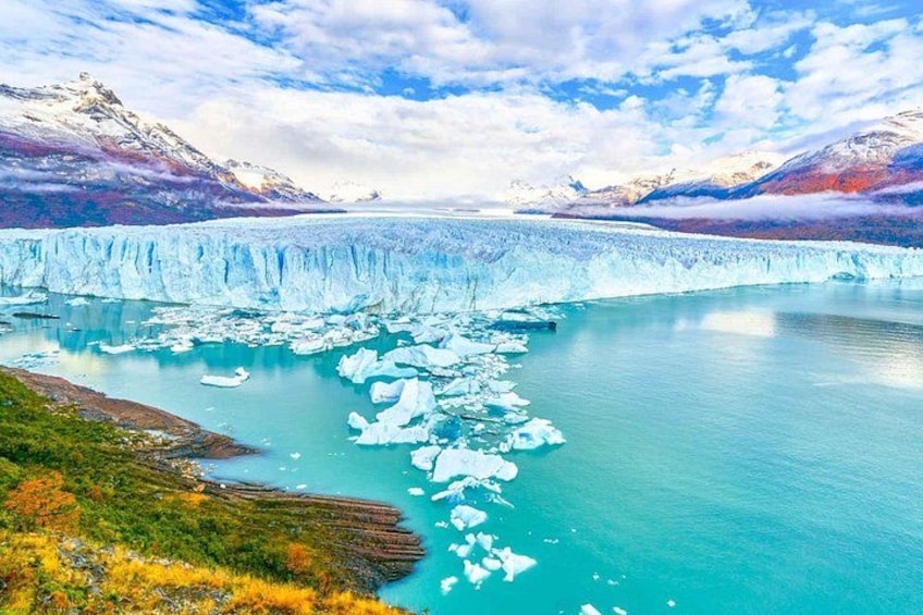Un ghiacciaio con iceberg in un lago turchese, circondato da montagne e vegetazione. 2
