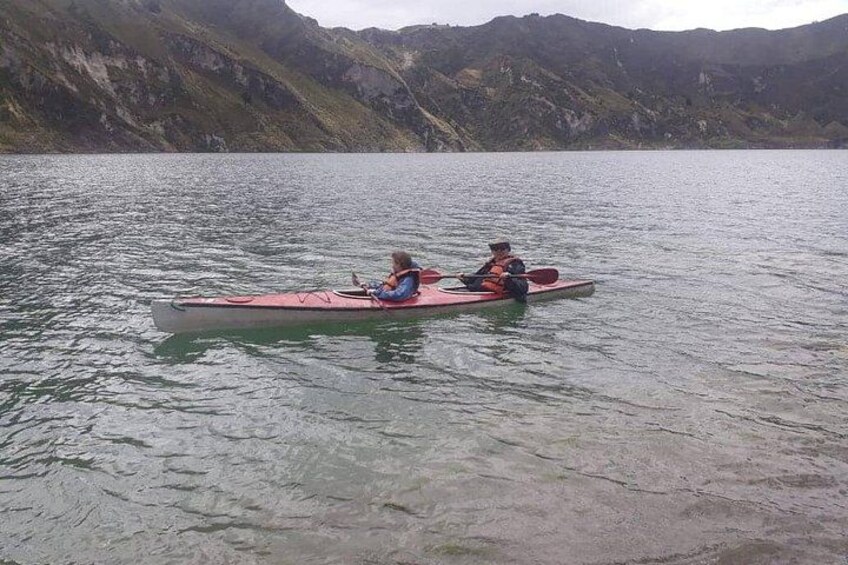 Two people in a canoe on a calm lake surrounded by mountains. 3
