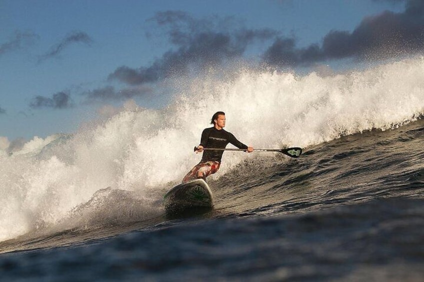 A person surfing a wave with a paddleboard. 4