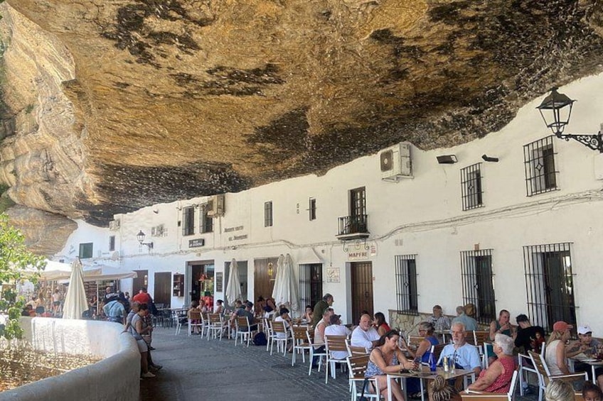 A café under a rock formation with people dining. 3