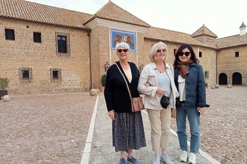 Three people standing in front of a historic building with a tiled roof and stone walls. 2