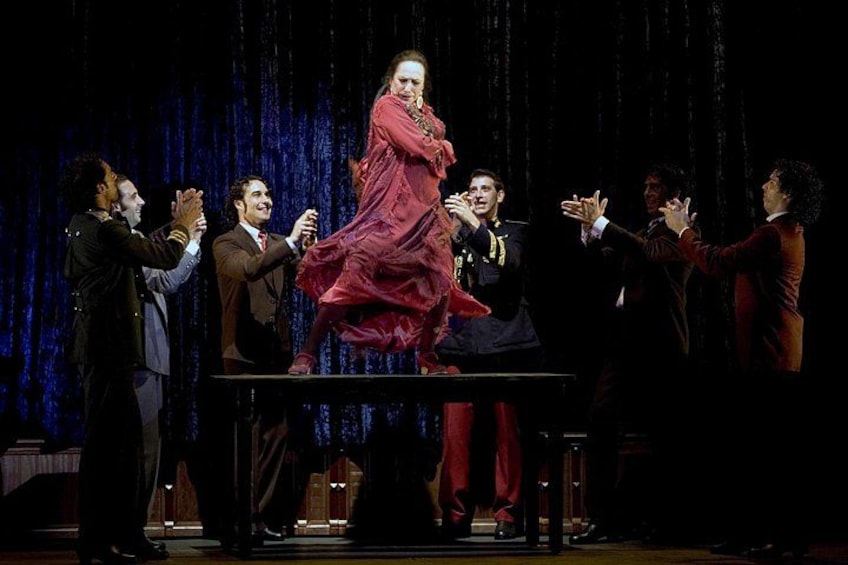 A stage with a person in a red dress being lifted by others. 2