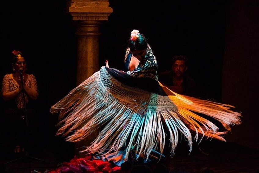 A person in a flowing, multicolored dress performing a dance. 1