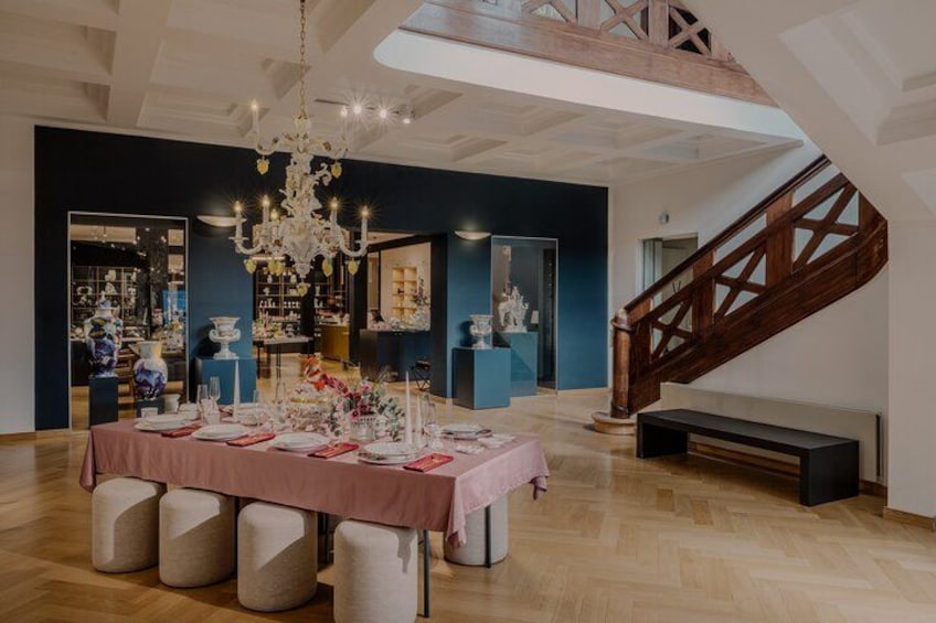 A dining room with a large table set for a meal, a chandelier, and a staircase. 3