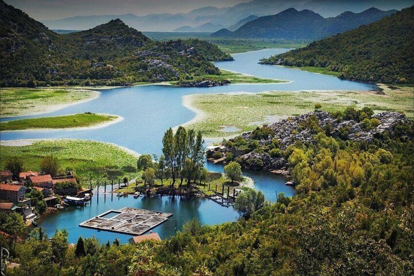 A river winding through a valley with a small dock and buildings. 1