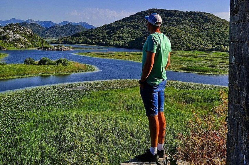 A man standing by a river with a mountainous landscape in the background. 2