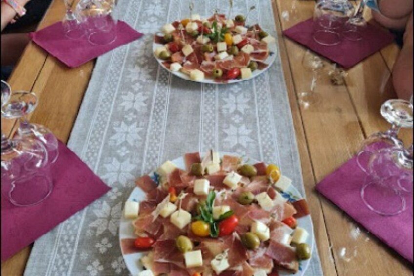 A wooden table with two plates of assorted cheeses and meats, surrounded by wine glasses. 4