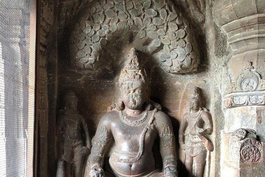 A stone sculpture of a deity with a crown, surrounded by smaller figures. 1