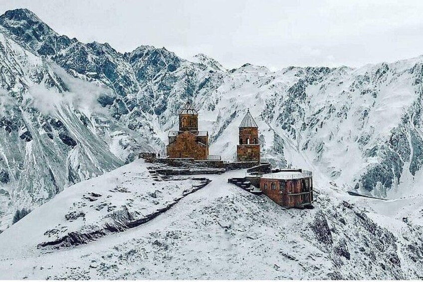 Een berglandschap bedekt met sneeuw, met een kerk en een klokkentoren. 3