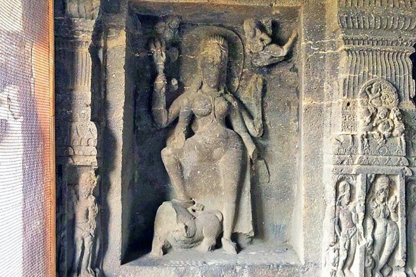 A stone sculpture of a deity with a lion, intricate carvings, and a detailed base. 1