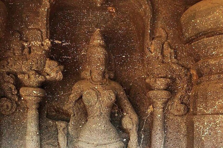 A weathered stone sculpture of a deity with multiple arms, set against a backdrop of ancient stone architecture. 5