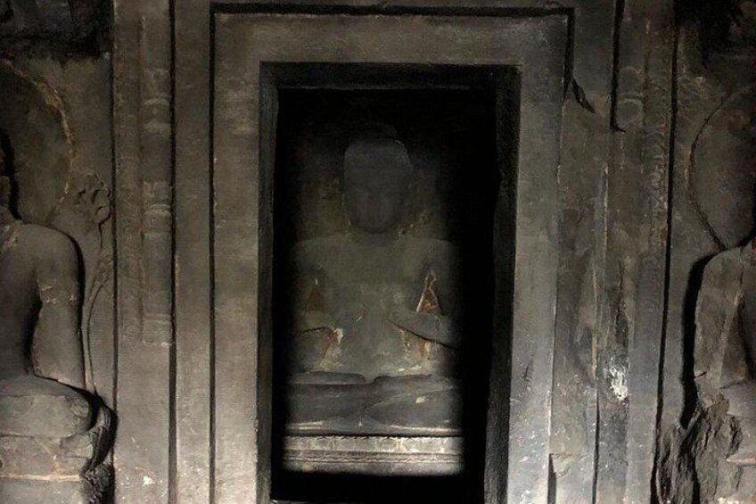 A stone Buddha statue in a niche, surrounded by similar statues. 5