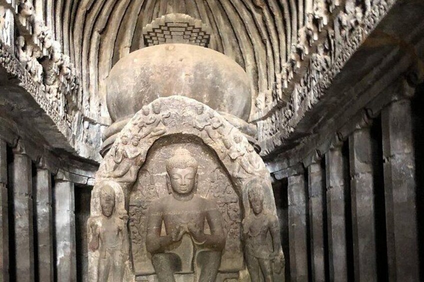 A stone Buddha statue with intricate carvings, set within a stone archway. 3