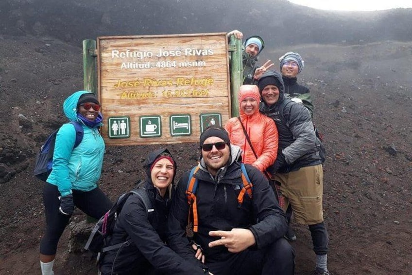 A group of hikers at a mountain trail sign. 1