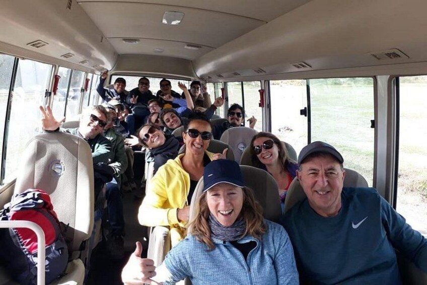 A group of people inside a bus, some holding up their hands. 4