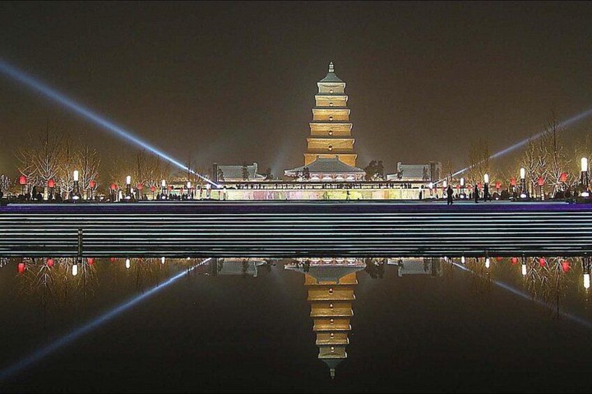 A pagoda with a reflection in the water, surrounded by trees and lights. 5