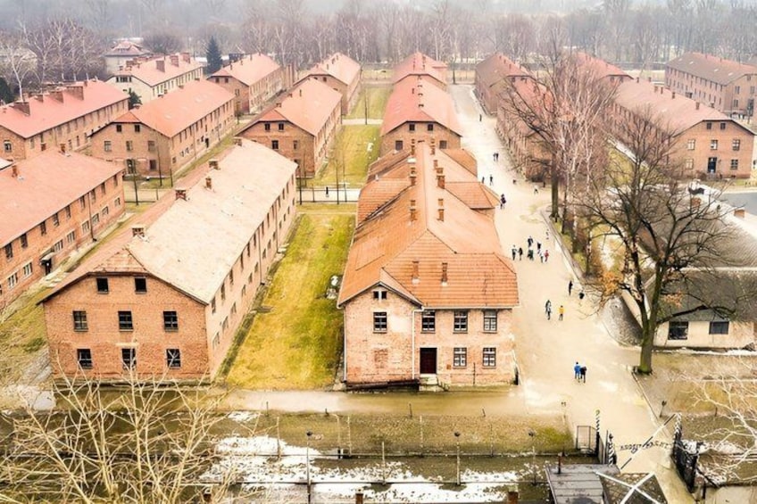 Un vaste ensemble de bâtiments en briques, composé de plusieurs structures plus petites, avec une cour centrale et un chemin menant à une porte. 3