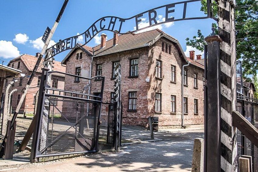 Ein historisches Gebäude mit einem Metallgitter und der Inschrift 'ARBEIT MACHT FREI'. 1