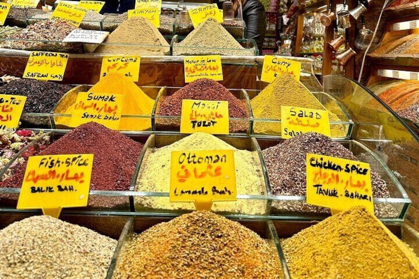 A variety of spices displayed in glass containers with labels in multiple languages. 3