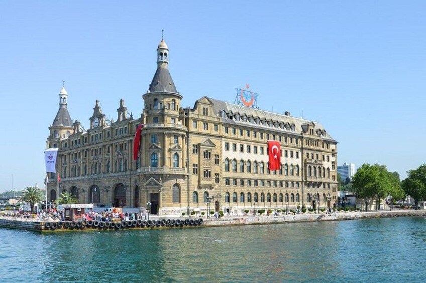 Ein großes, historisches Gebäude mit einer markanten Flagge, Blick auf das Wasser und einem wolkenlosen Himmel. 4